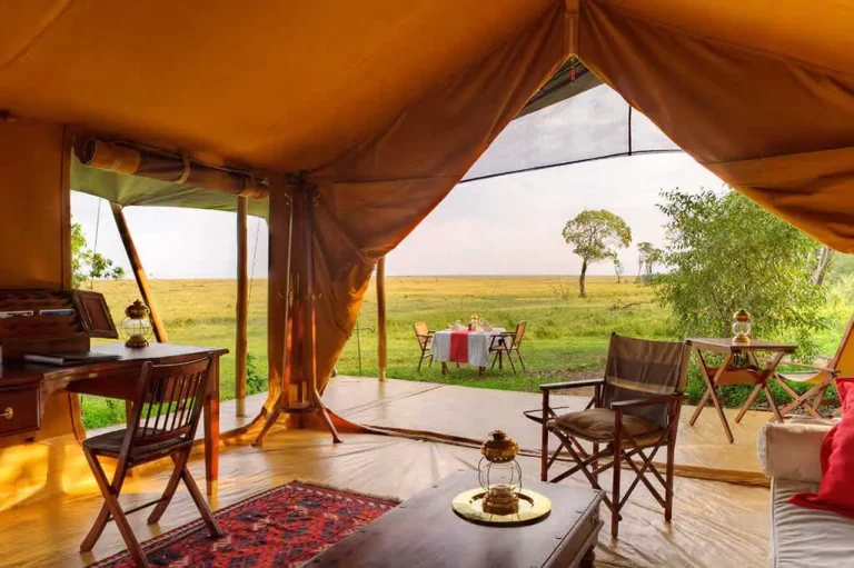 Luxury Kenya Safari Lodges in Maasai Mara featuring an elegant tented suite overlooking the savannah with wildlife views.