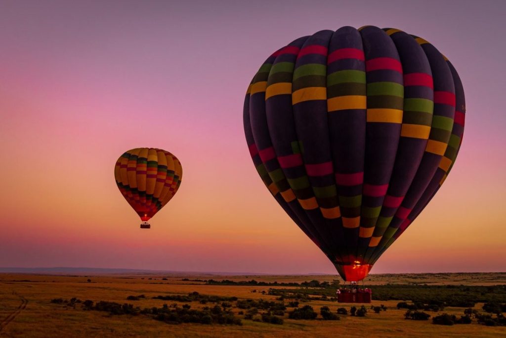 Hot Air Balloon Masai Mara safari floating above the Maasai Mara plains during sunrise with wildlife roaming across the savannah below