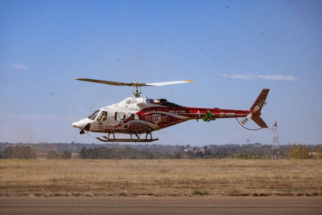 Air ambulance helicopter flying low over grassland during an emergency evacuation