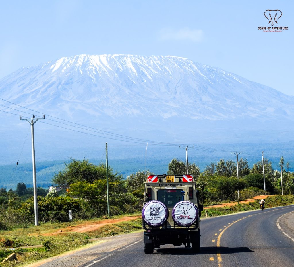 Safari jeep driving toward Mount Kilimanjaro near Amboseli