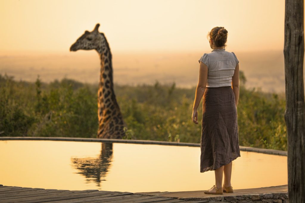 Traveller watching a giraffe reflected in water on FIT and GIT safaris in Kenya