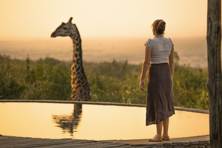 Traveller watching a giraffe reflected in water on FIT and GIT safaris in Kenya