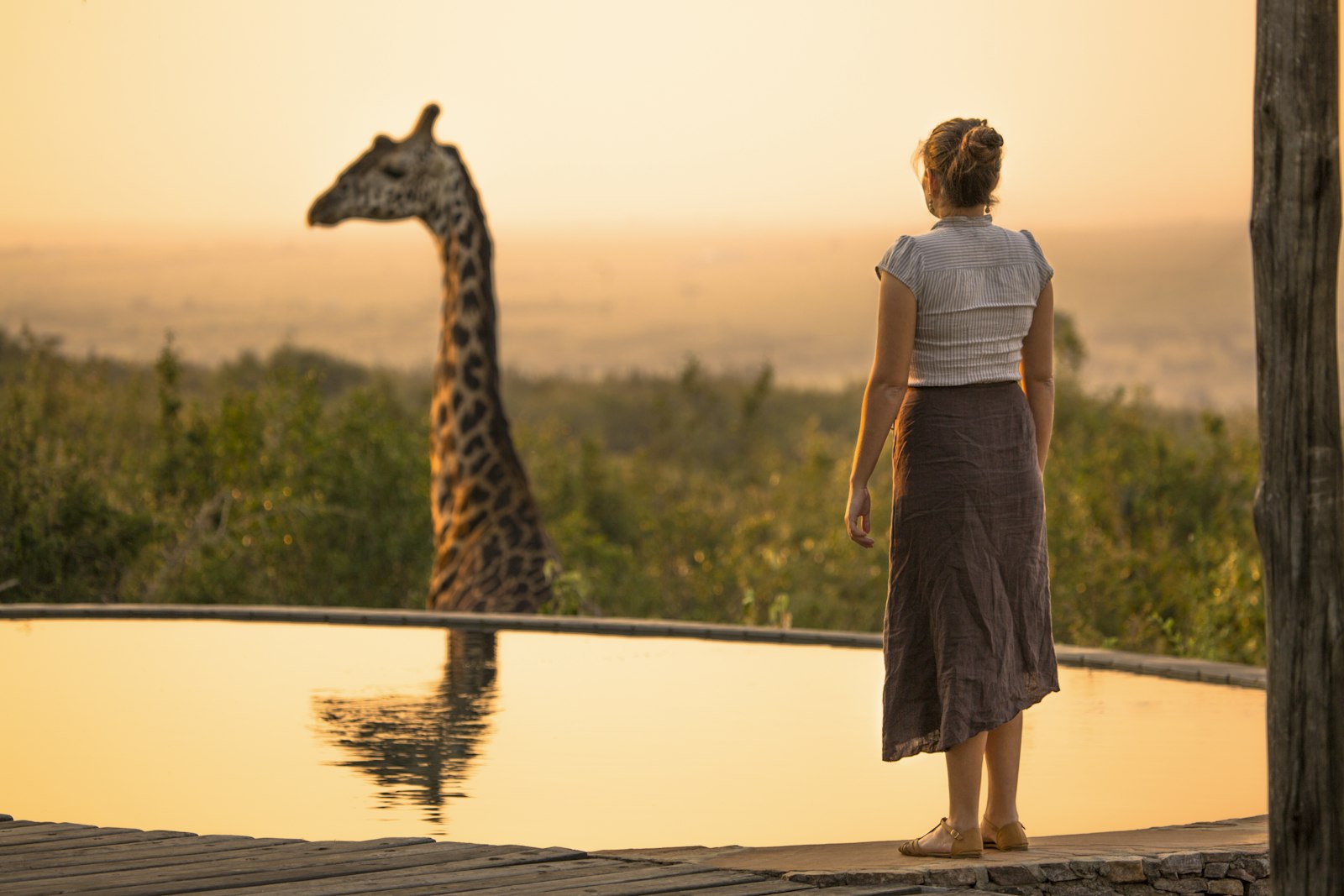Traveller watching a giraffe reflected in water on FIT and GIT safaris in Kenya
