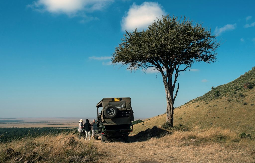 Book a safari with a local operator: safari vehicle parked beside a tree in Kenya