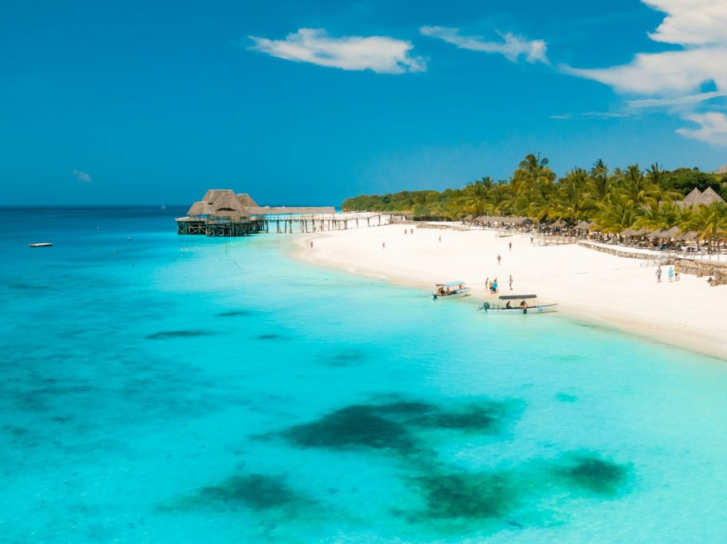 Nairobi to Zanzibar layover destination: white sand beach, palm trees and wooden pier in Zanzibar