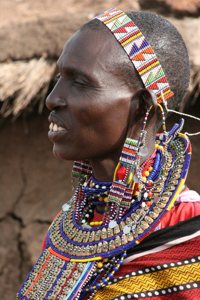 Kenya safari spending money on crafts: woman wearing colourful red, blue and yellow beaded necklaces