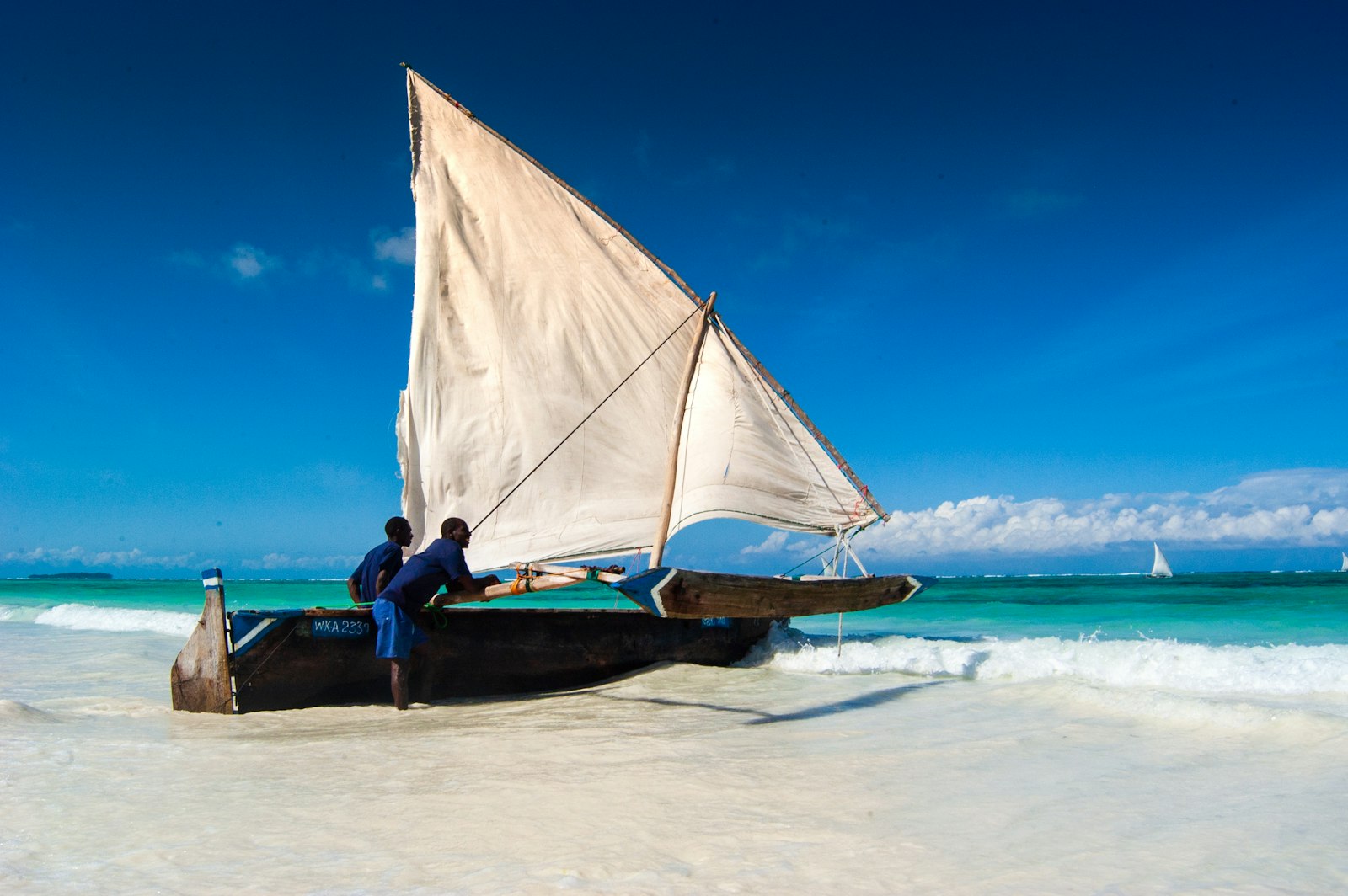 Man sitting on a traditional wooden sailing boat on Matemwe beach in Zanzibar at low tide