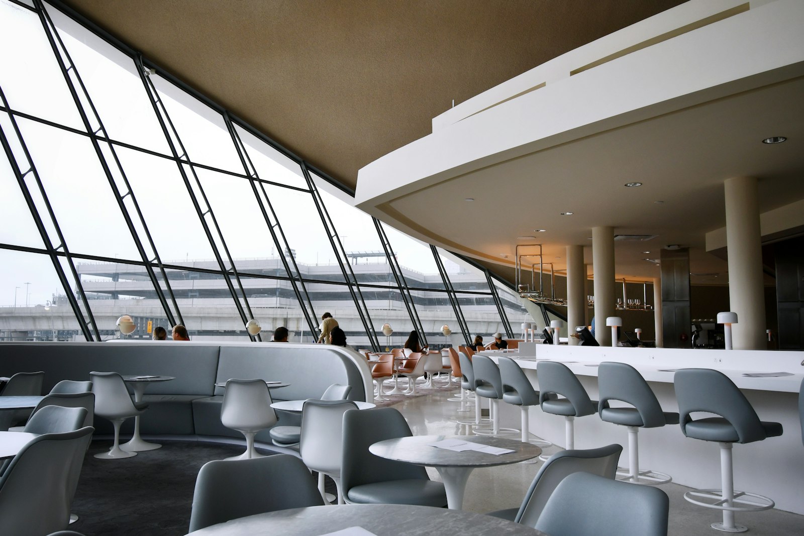 Passengers waiting on rows of seats inside a bright airport terminal before boarding