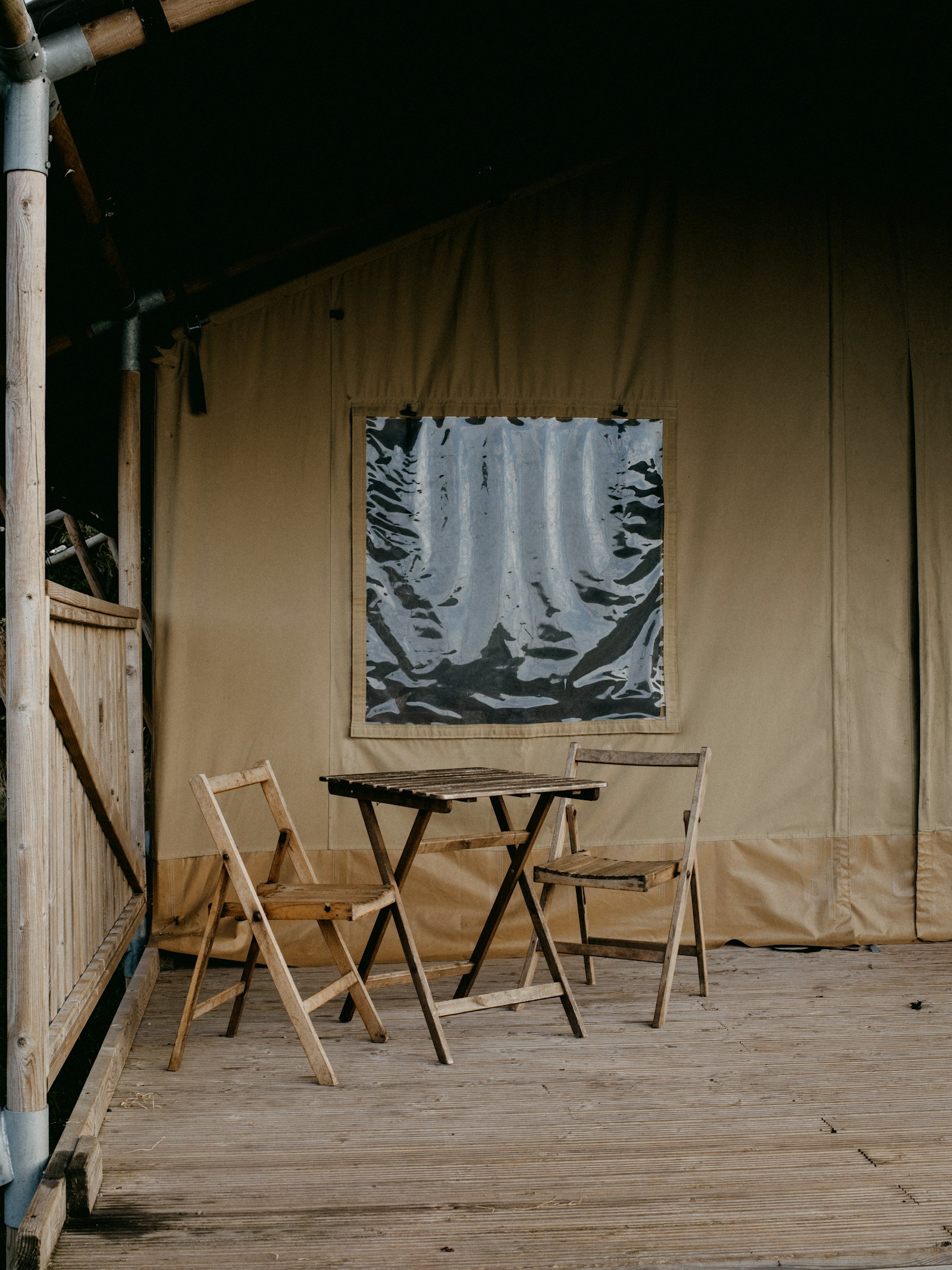 Canvas safari tent with a table and chairs set up on the veranda outside