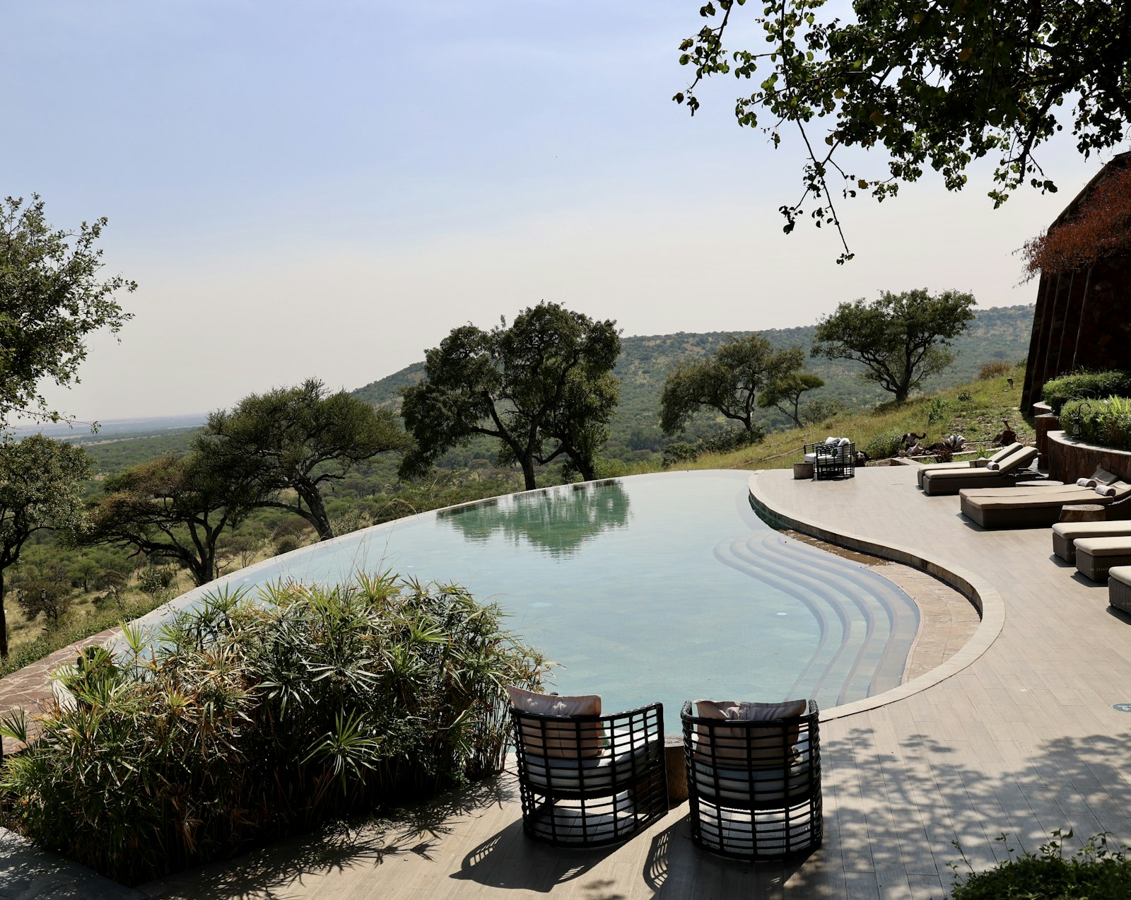 Safari lodge swimming pool and patio with sun loungers between game drives