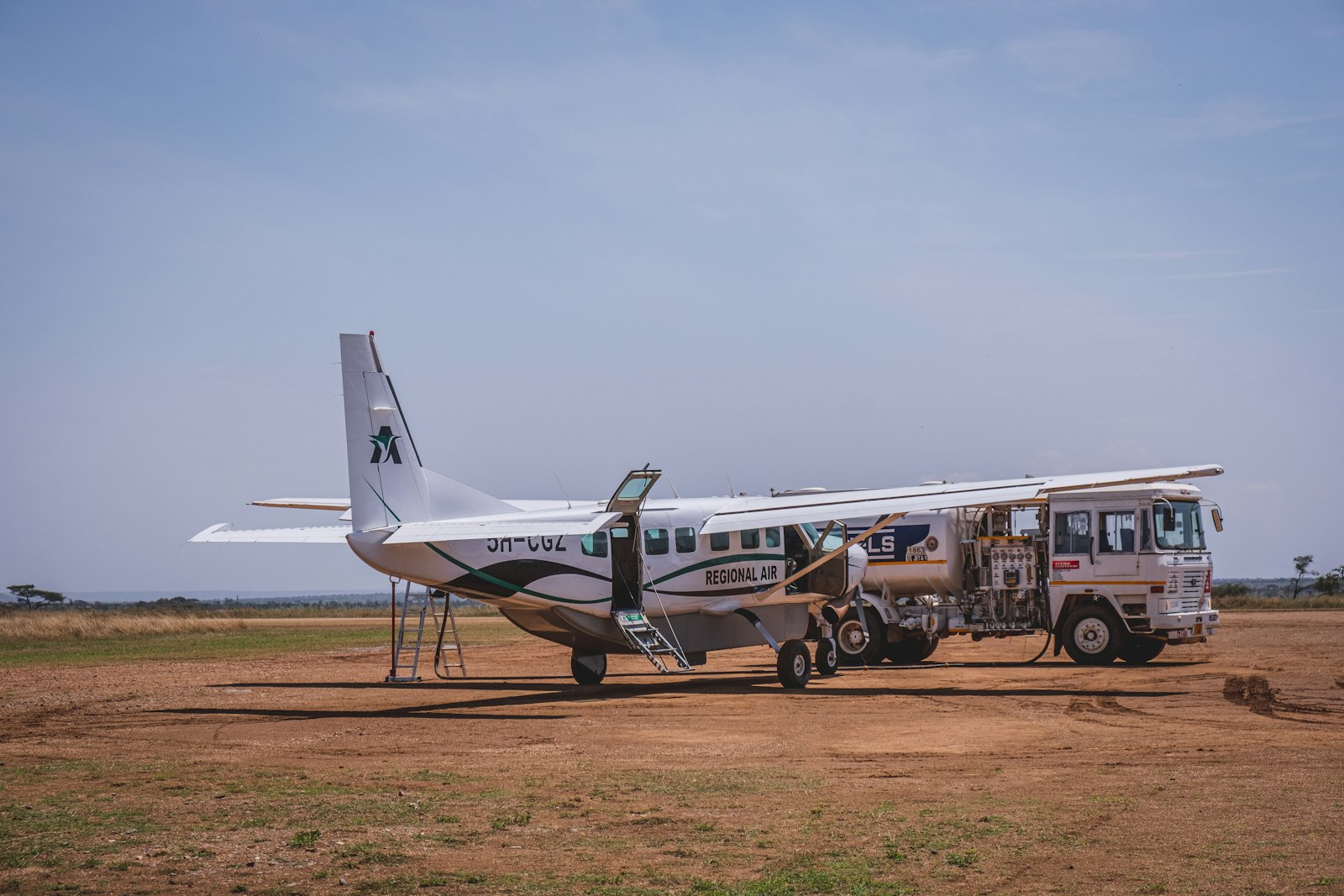 Small plane parked on a dirt field at a bush airstrip, waiting for safari passengers