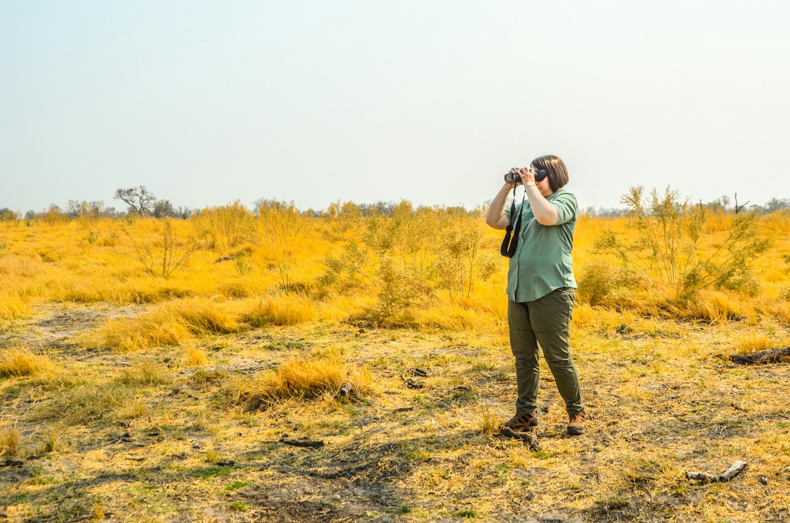 Traveller standing in an open field taking photographs with a camera on safari