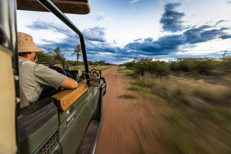 Safari vehicle on a dirt road to the gate, illustrating Kenya park fees for tour operators