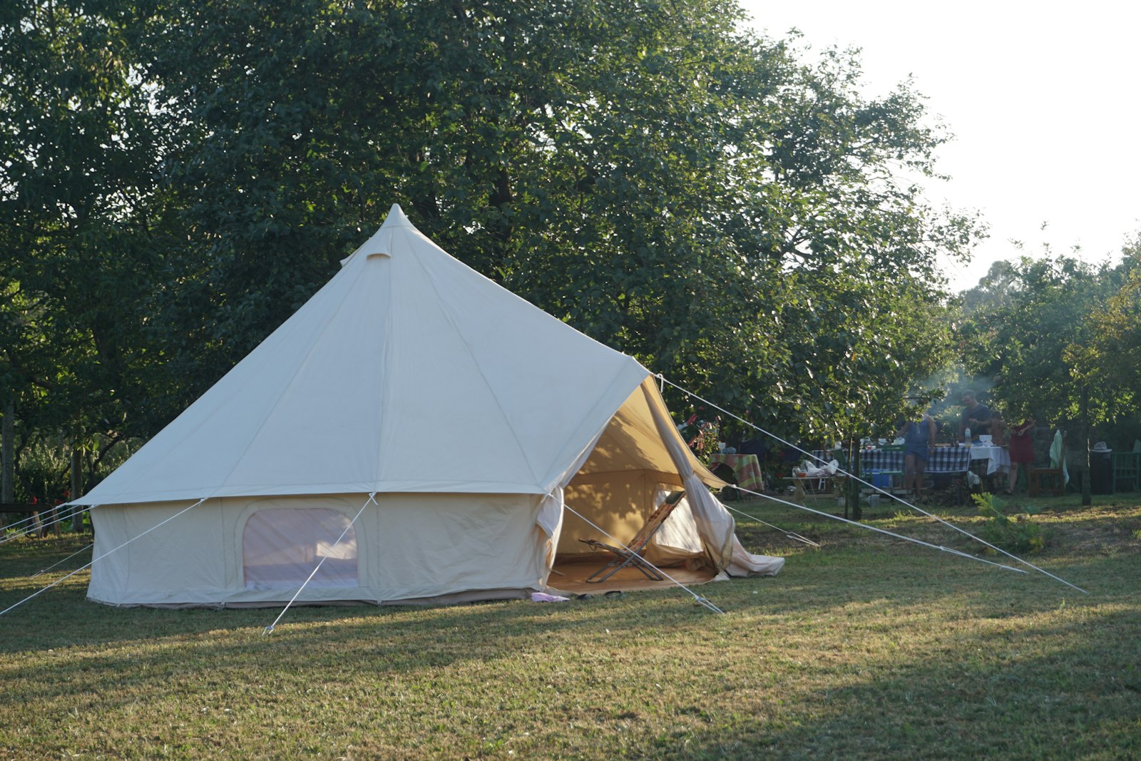 Safari tent: a large white canvas tent standing on open green grassland