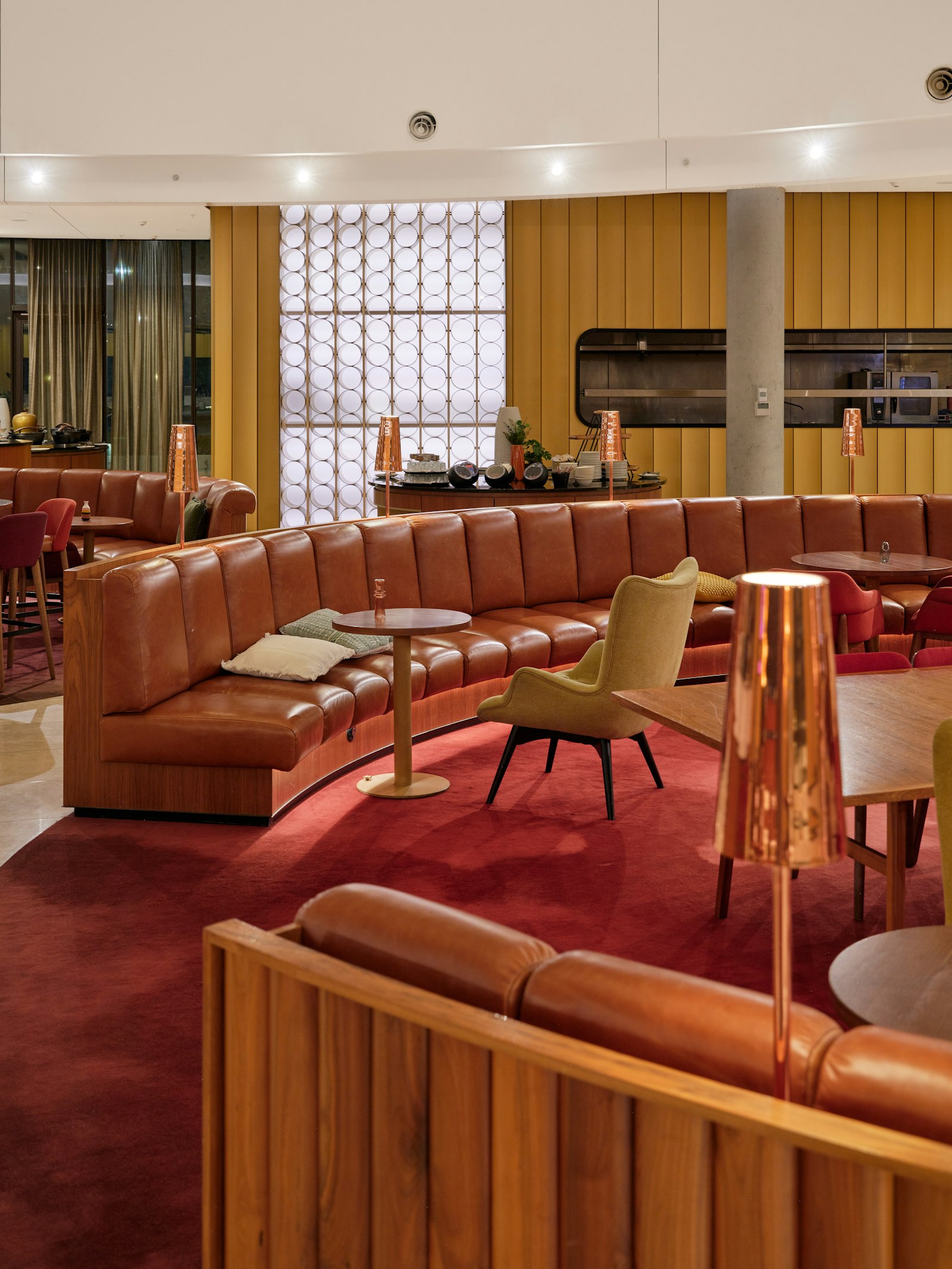 Modern airport lounge with curved leather seating and warm lighting for resting between flights