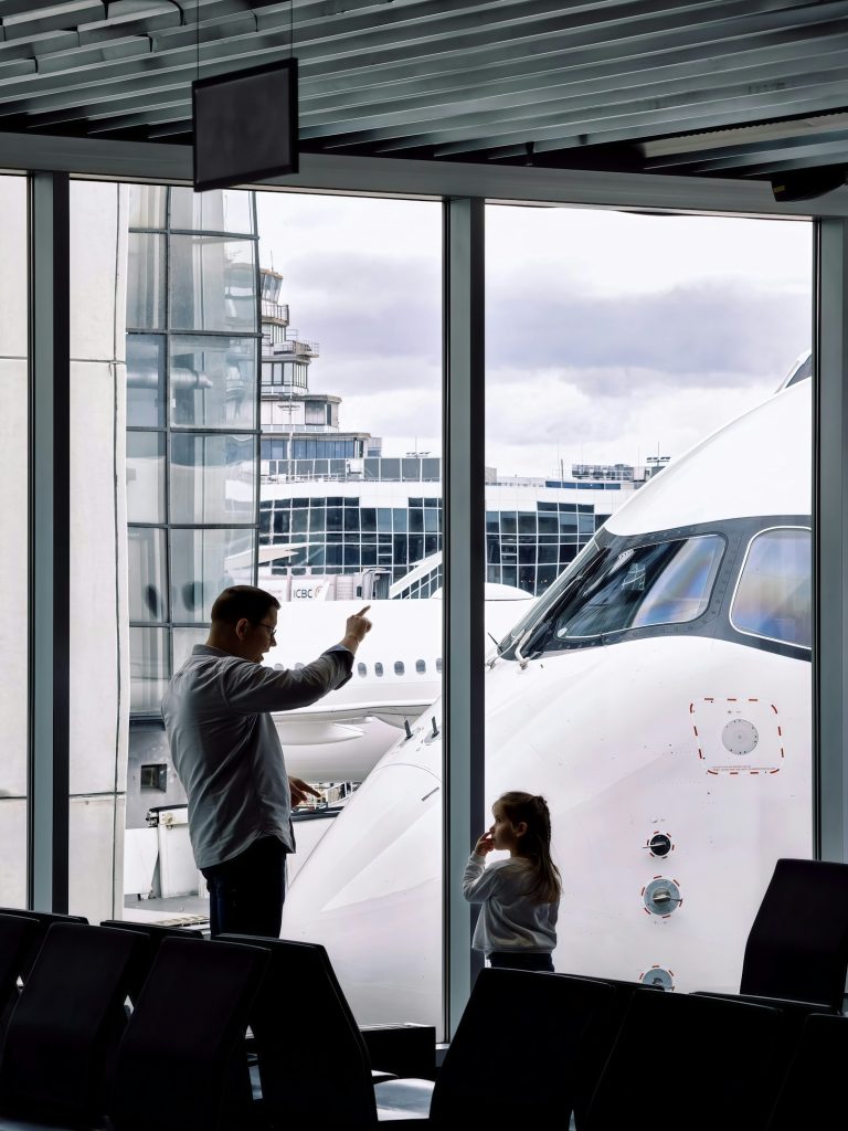 Father and young daughter watching planes at the gate during a Nairobi layover with kids