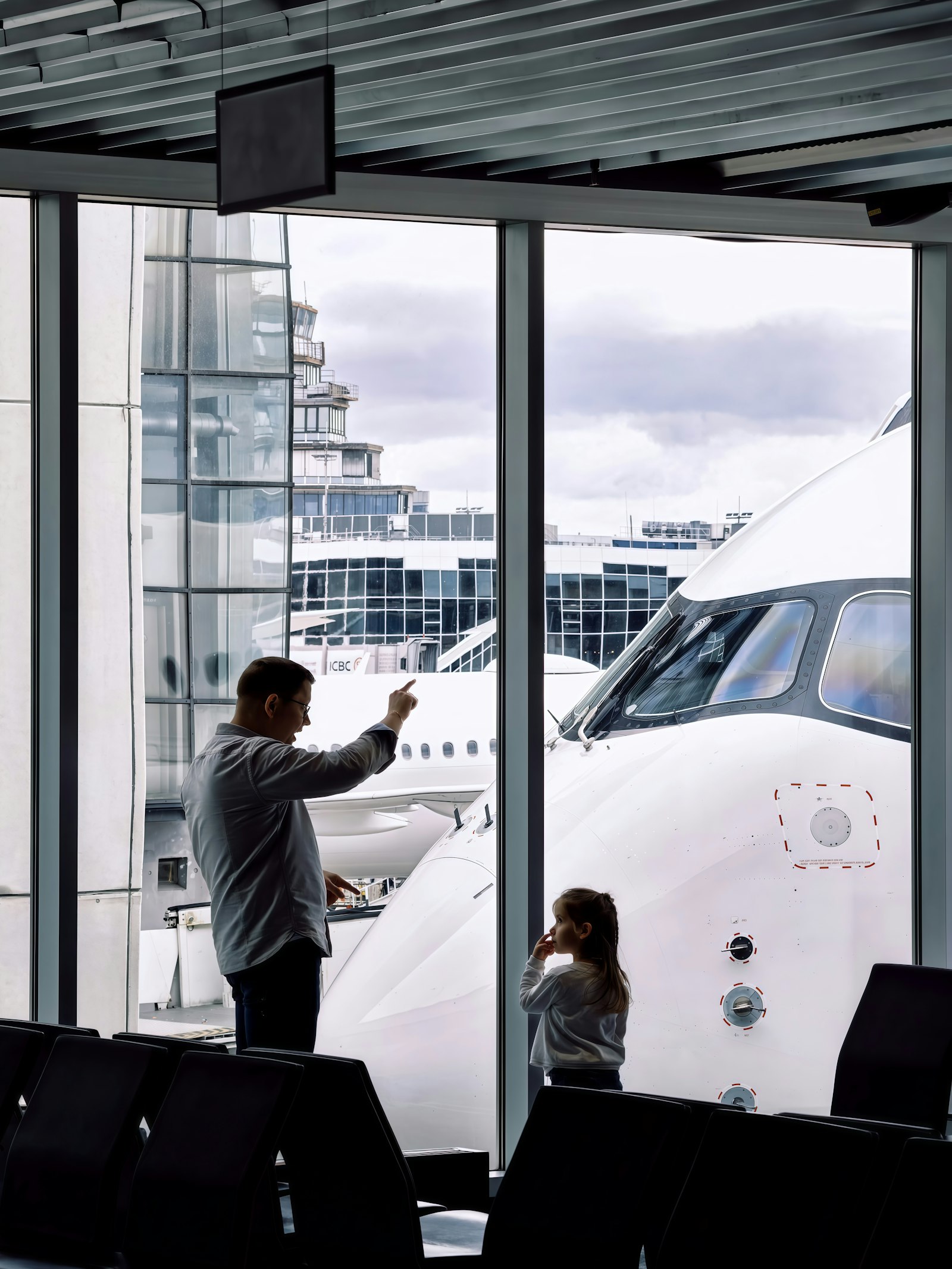 Father and young daughter watching planes at the gate during a Nairobi layover with kids