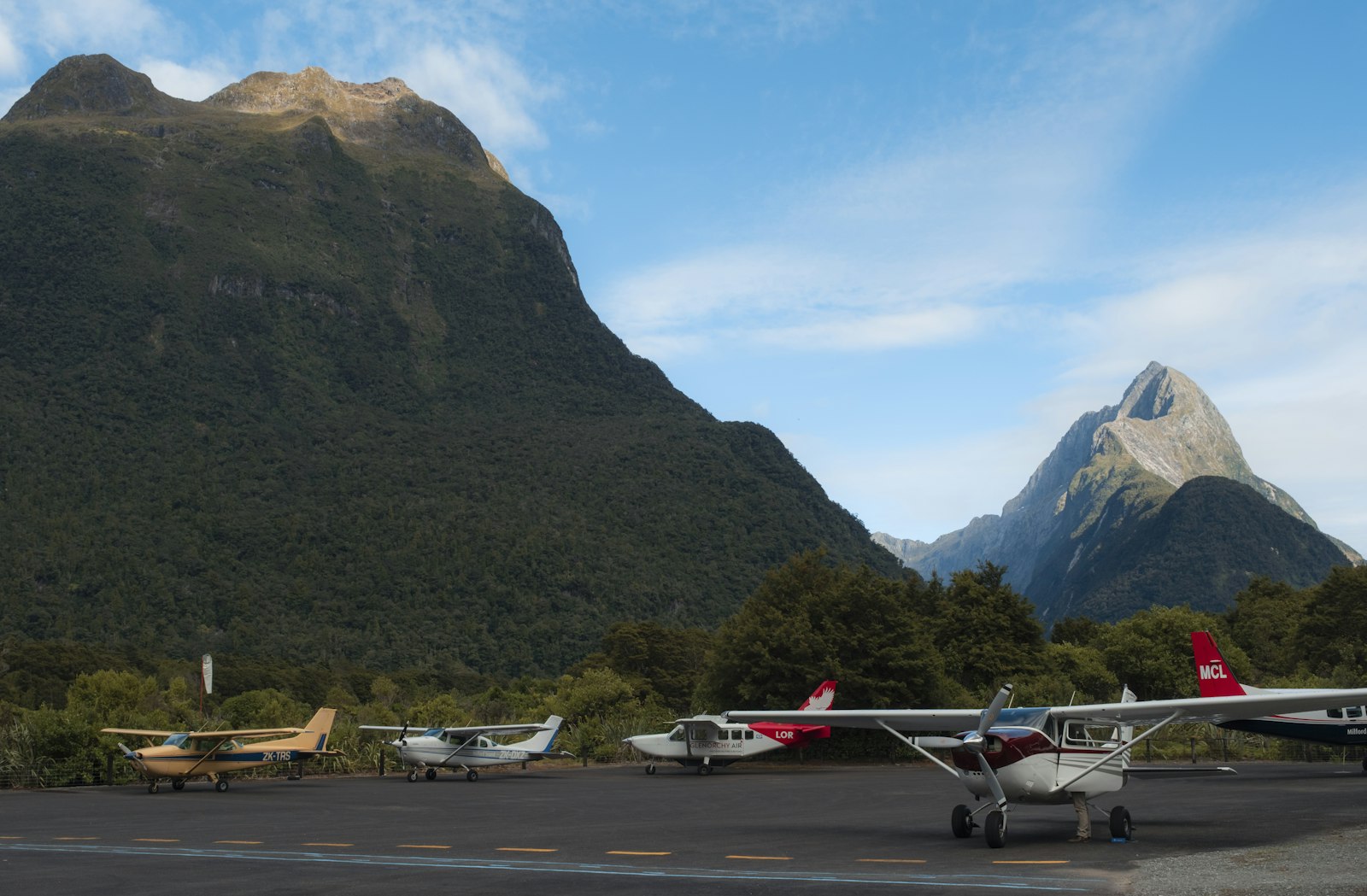 Row of small aircraft parked on an apron with mountains behind, typical of safari flight hubs